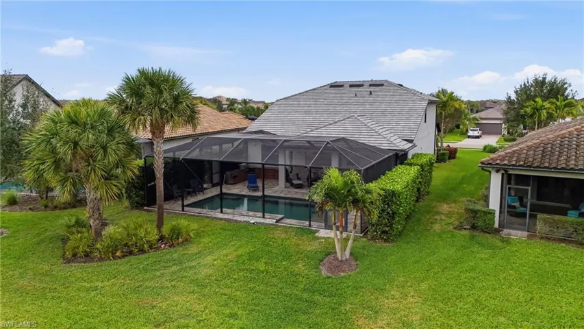 Rear view of house featuring a sunroom, a lanai, an outdoor pool, and a lawn