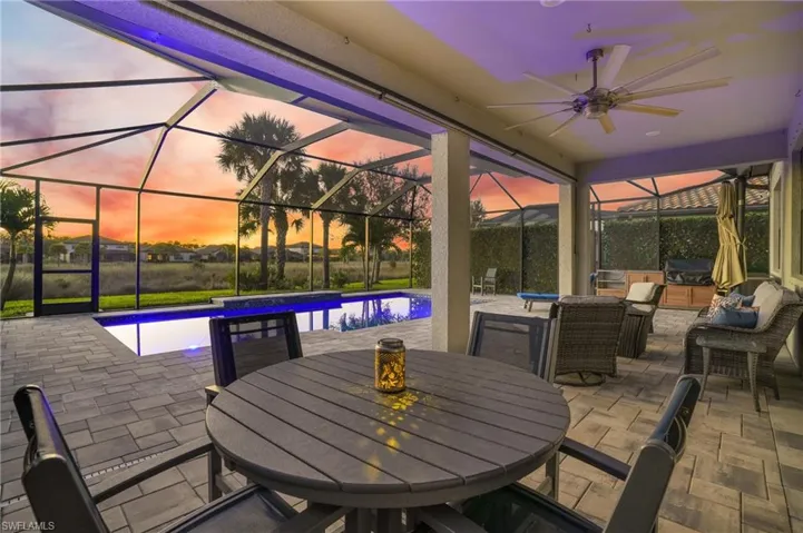 Patio terrace at dusk with a patio, glass enclosure, a sunroom, and an outdoor pool