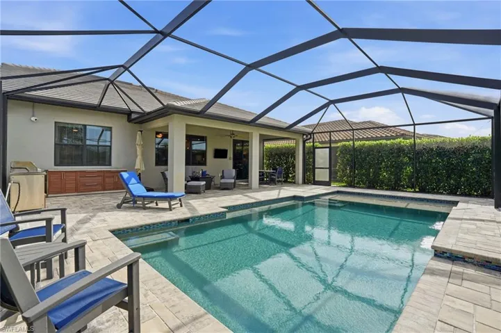 Outdoor pool with a sunroom, glass enclosure, and a patio area
