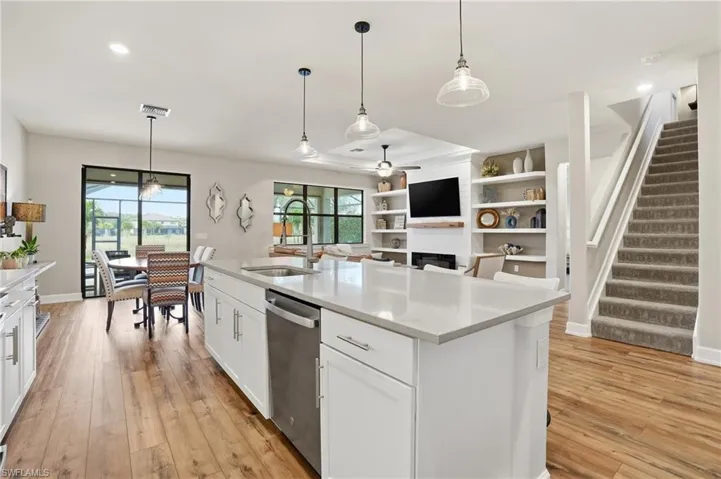 Kitchen featuring a fireplace, pendant lighting, white cabinets, light stone countertops, and light wood-type flooring
