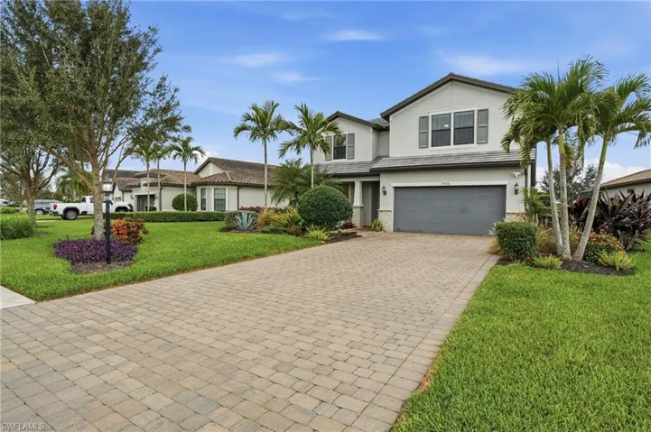 View of front of property featuring a garage, a front yard, decorative driveway, stucco siding, and stone siding