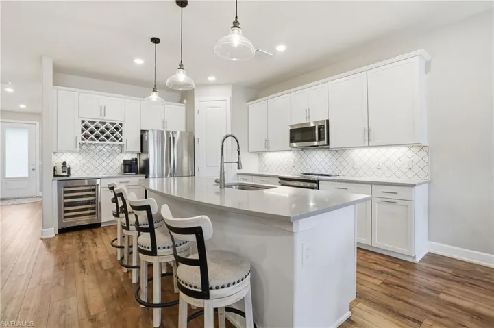 Kitchen featuring white cabinetry, stainless steel appliances, a kitchen island with sink, a kitchen breakfast bar, and recessed lighting