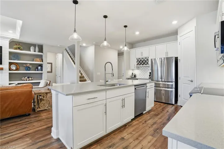 Kitchen with open floor plan, decorative light fixtures, appliances with stainless steel finishes, white cabinetry, and recessed lighting