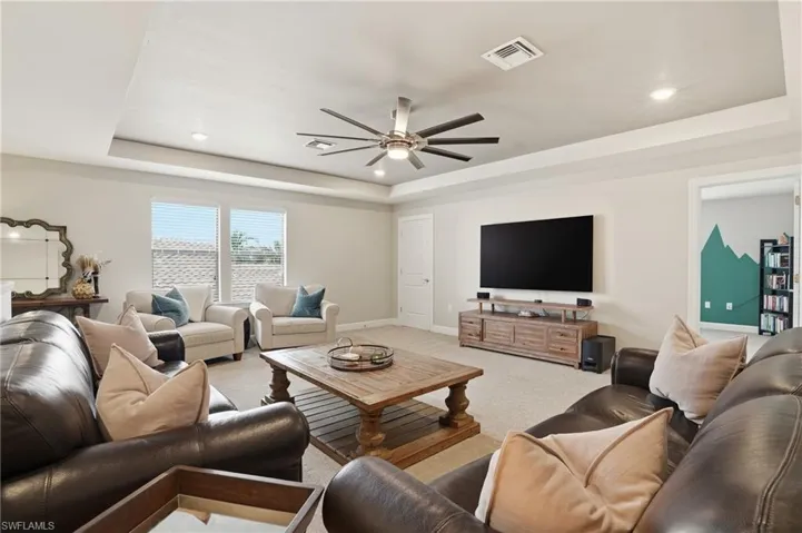 Carpeted living area with a tray ceiling, ceiling fan, and recessed lighting