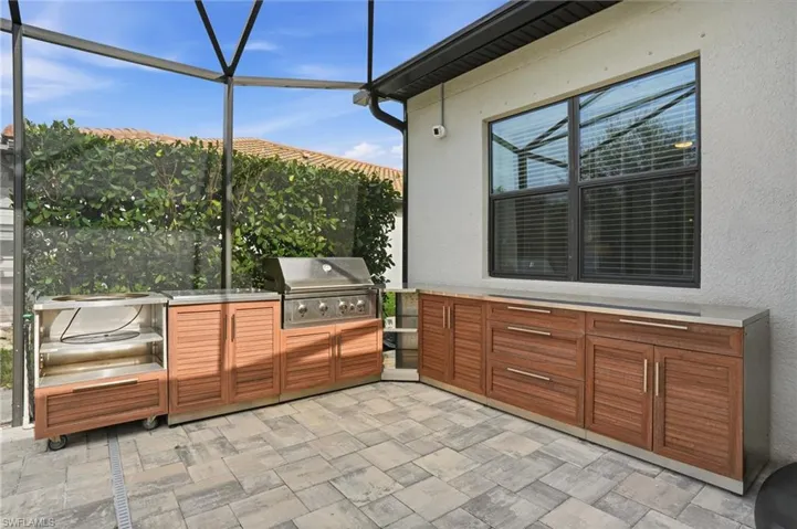 View of patio / terrace with a sunroom, a lanai, and an outdoor kitchen