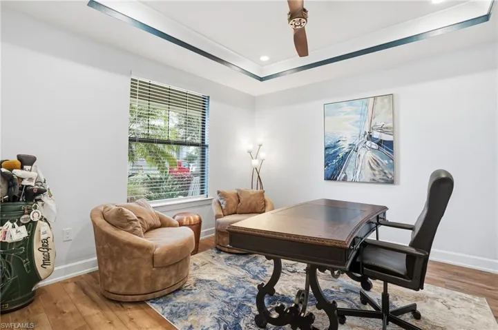 Office area featuring hardwood / wood-style flooring, a raised ceiling, recessed lighting, and a ceiling fan