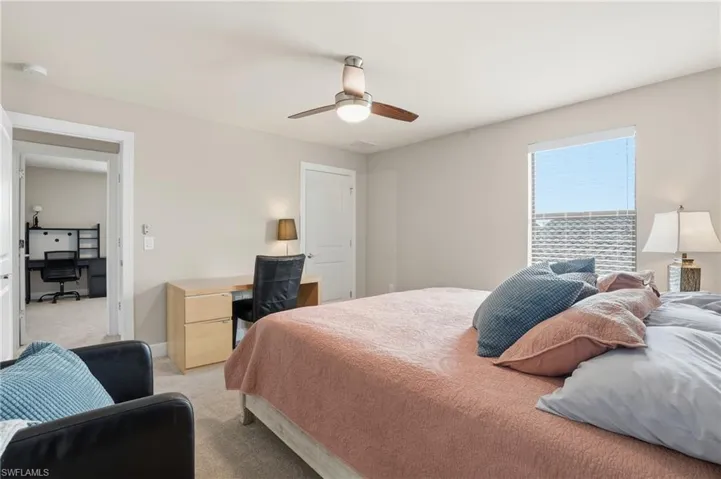 Bedroom with light colored carpet, an office area, and ceiling fan