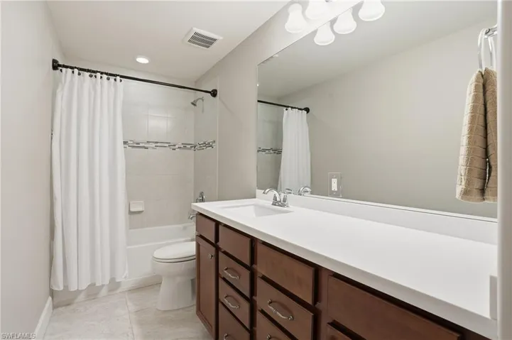 Bathroom with shower / tub combo with curtain, vanity, and light tile patterned flooring