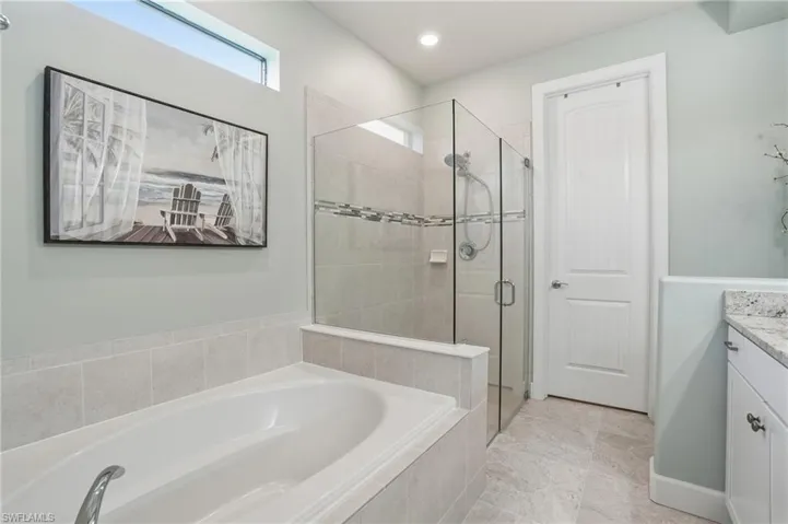 Full bath featuring vanity, a bath, a stall shower, and recessed lighting