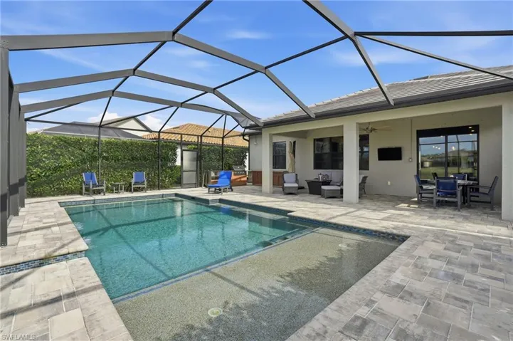 Outdoor pool with a sunroom, glass enclosure, a patio, and outdoor dining area