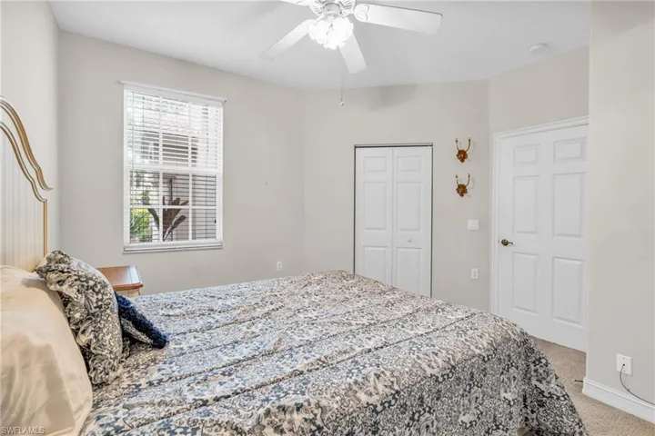 Carpeted bedroom with ceiling fan and a closet