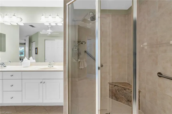 Bathroom with tile patterned flooring, vanity, ceiling fan, and a shower with shower door