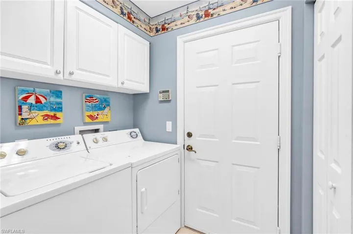Washroom with washer and clothes dryer and cabinets