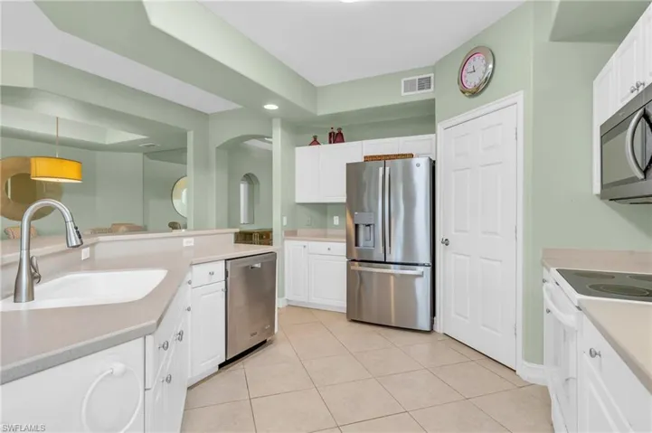Kitchen with light tile patterned flooring, stainless steel appliances, pendant lighting, sink, and white cabinets