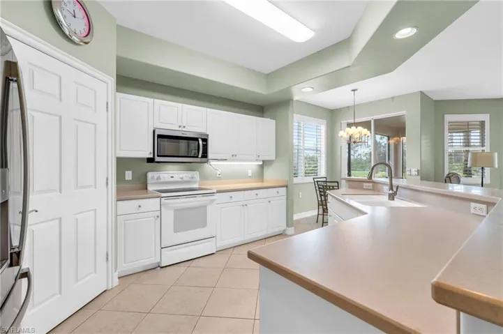 Kitchen with stainless steel appliances, a healthy amount of sunlight, sink, and white cabinets