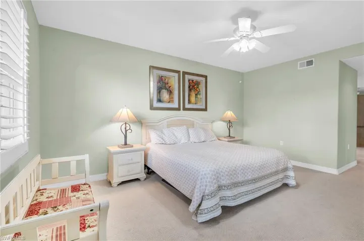 Bedroom with ceiling fan and light colored carpet