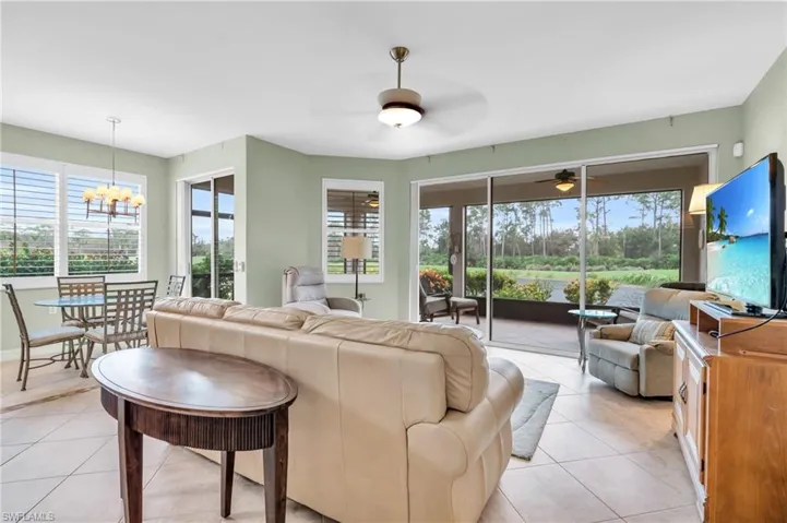 Tiled living room featuring a wealth of natural light and ceiling fan with notable chandelier