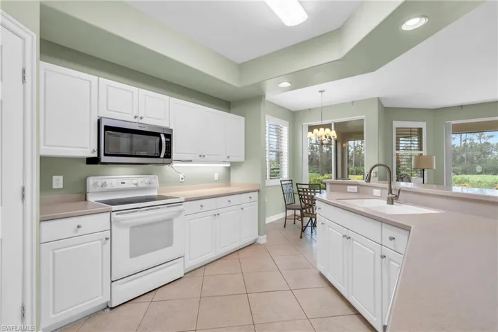 Kitchen with white cabinetry, sink, an inviting chandelier, pendant lighting, and electric stove