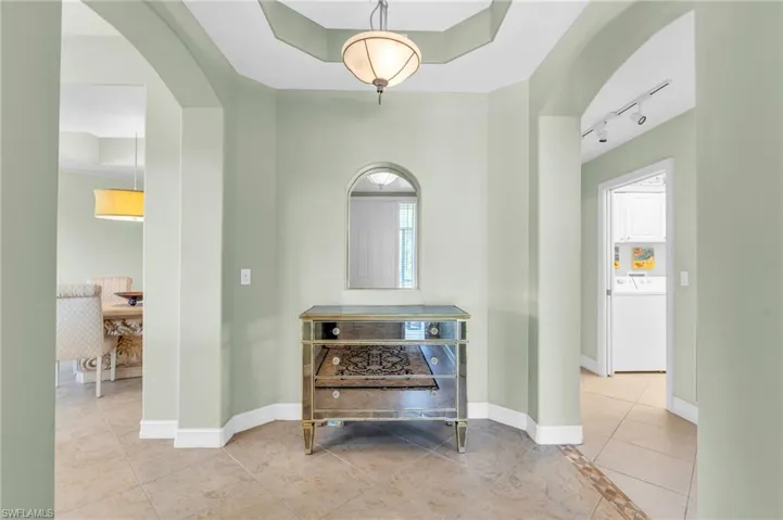 Corridor with light tile patterned floors, track lighting, and washer / clothes dryer