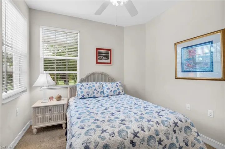 Carpeted bedroom with ceiling fan and multiple windows