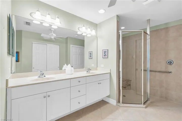 Bathroom with vanity, a shower with shower door, tile patterned flooring, and ceiling fan