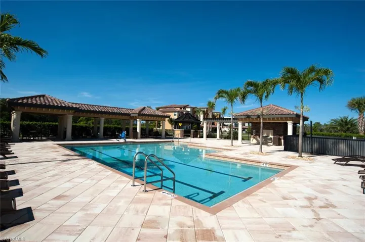 Resort-style swimming pool featuring lane markers, a tiled pool deck, and integrated shaded pavilions with terra cotta roof tiles