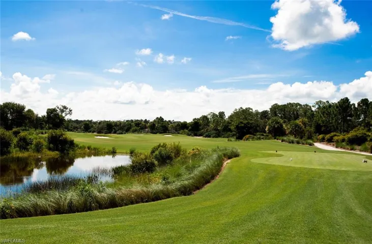 Expansive golf course green with manicured turf, sand traps, and a water feature surrounded by natural foliage