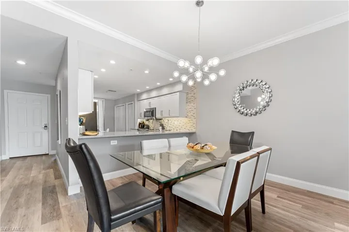 Dining room featuring a notable chandelier, light hardwood / wood-style floors, and ornamental molding