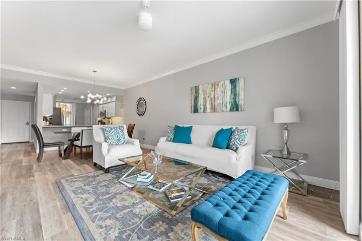 Living room featuring light hardwood / wood-style flooring, ornamental molding, and a notable chandelier