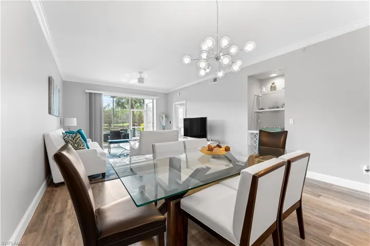 Dining space featuring light hardwood / wood-style flooring, an inviting chandelier, and ornamental molding