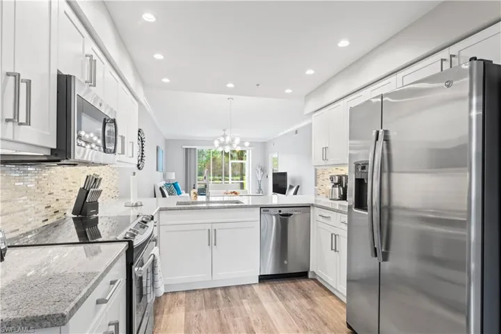 Kitchen featuring backsplash, sink, kitchen peninsula, appliances with stainless steel finishes, and white cabinetry