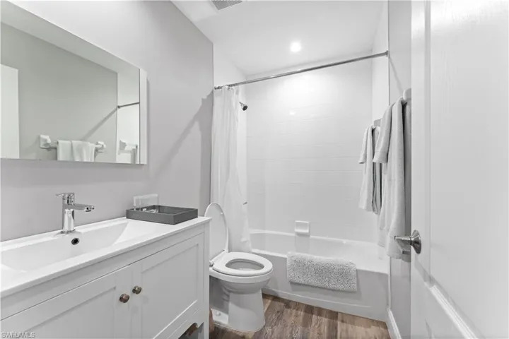 Full bathroom featuring toilet, vanity, shower / bath combo, and hardwood / wood-style flooring