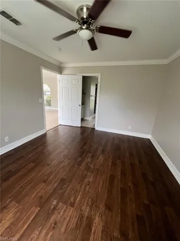 Unfurnished room with crown molding, dark wood-style flooring, ceiling fan, and a textured ceiling