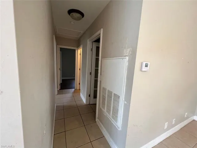 Corridor with light tile patterned floors and attic access