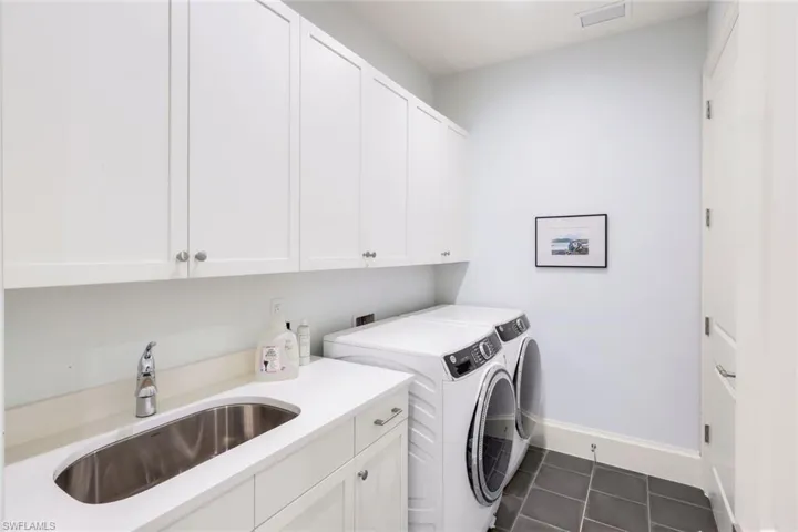 Laundry area with washer and dryer, cabinet space, and dark tile patterned floors