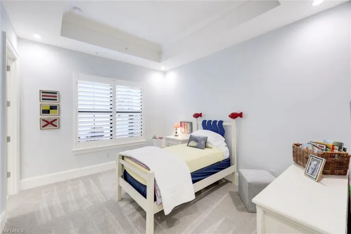 Bedroom with a raised ceiling, light carpet, and recessed lighting