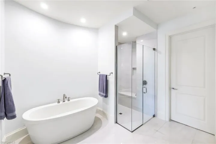 Full bathroom featuring a shower stall, a freestanding bath, light tile patterned floors, and recessed lighting