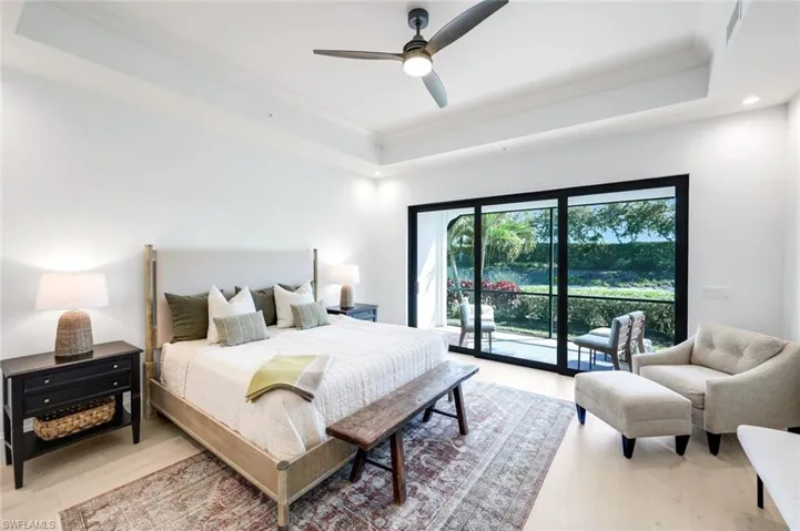 Bedroom with a tray ceiling, crown molding, access to exterior, a ceiling fan, and light wood-type flooring