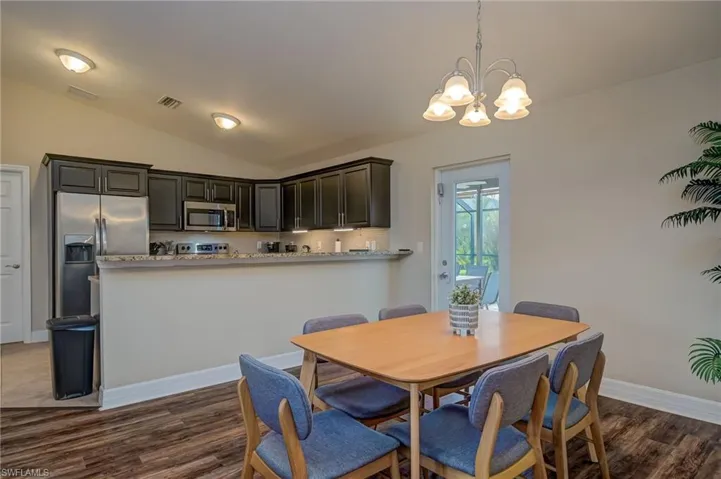 Dining room featuring vaulted ceiling, an inviting chandelier, and dark hardwood / wood-style flooring