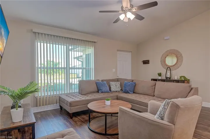 Living room featuring lofted ceiling, dark hardwood / wood-style floors, and ceiling fan
