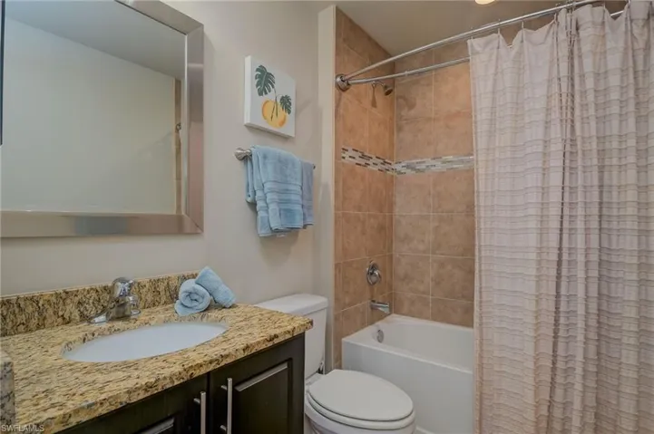 Full bathroom with shower / bath combo, toilet, and large vanity