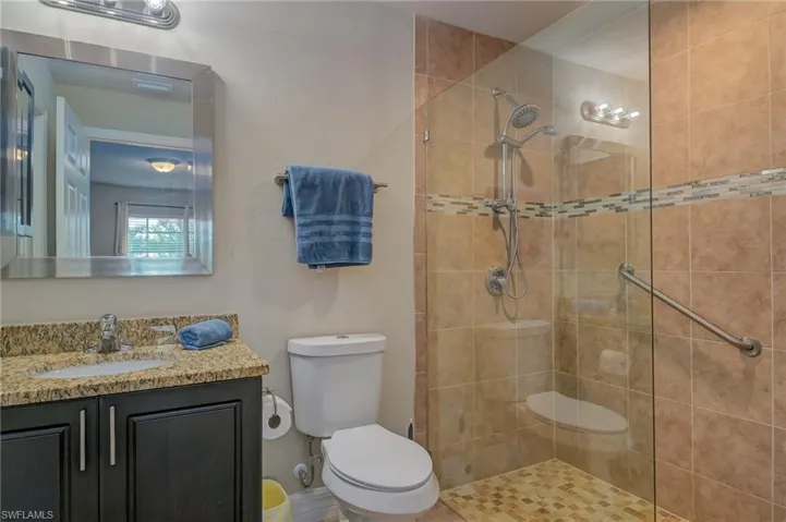 Bathroom with tiled shower, oversized vanity, and toilet
