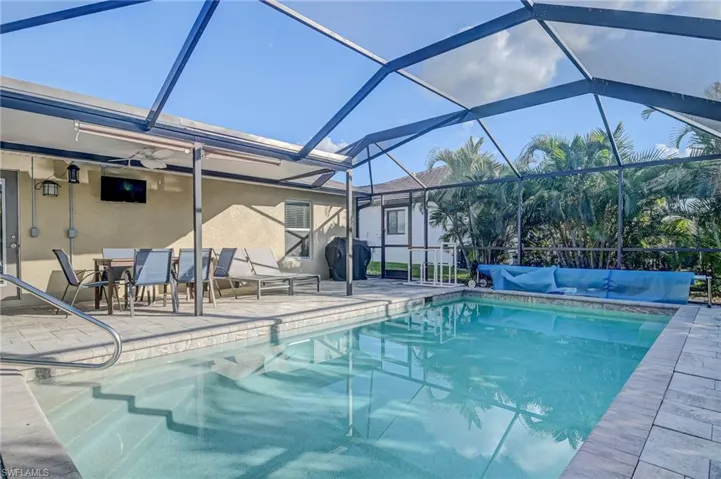 View of swimming pool with glass enclosure and a patio area