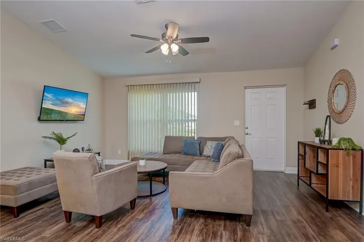 Living room featuring dark wood-type flooring, ceiling fan, and vaulted ceiling
