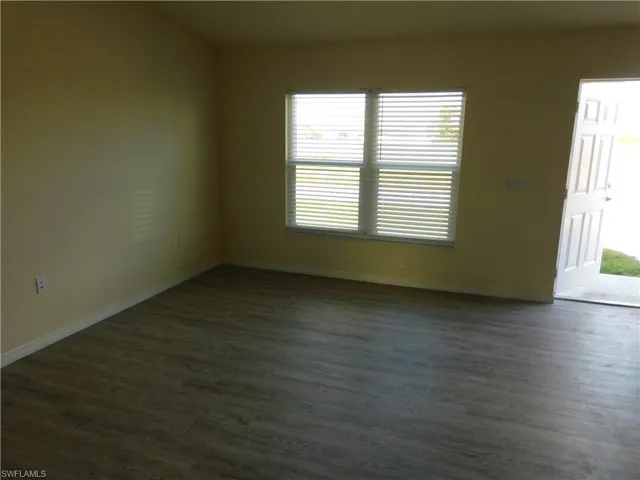 Empty room featuring dark wood-style flooring and baseboards