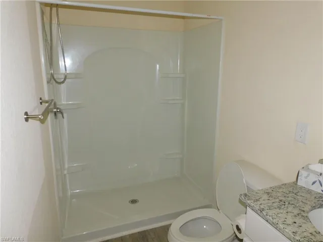 Full bath featuring a stall shower, vanity, and wood finished floors