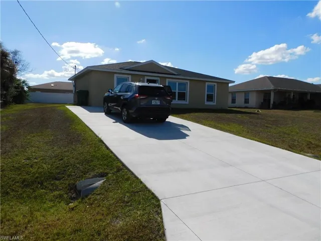 Single story home with a front yard, stucco siding, and concrete driveway
