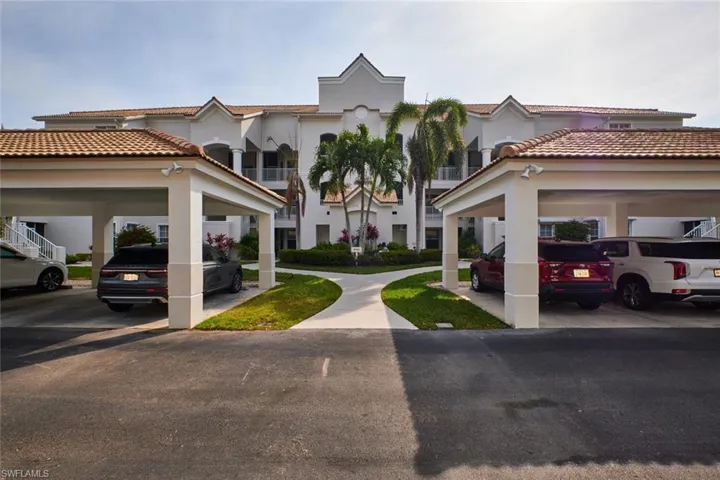 View of front of home with stucco siding, a tiled roof, and covered parking