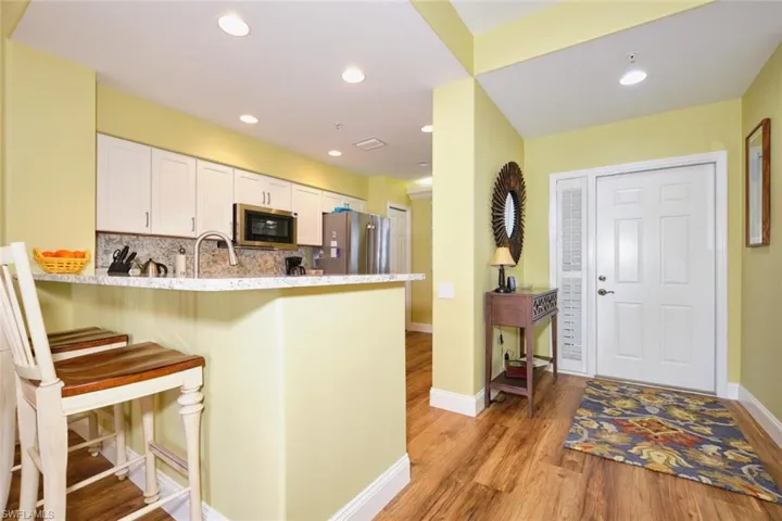 Kitchen featuring white cabinetry, backsplash, light wood-style flooring, a peninsula, and appliances with stainless steel finishes