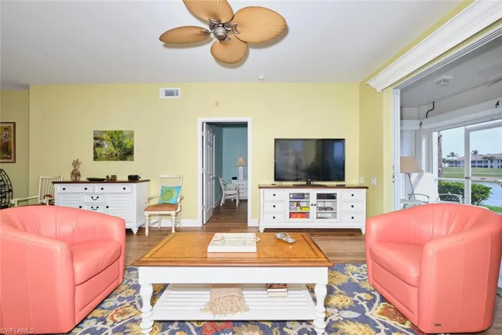 Living room featuring baseboards, visible vents, wood finished floors, and a ceiling fan